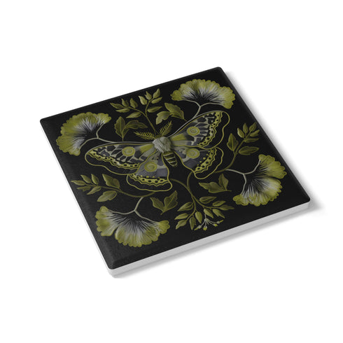 Square black ceramic coaster featuring a detailed chartreuse luna moth illustration surrounded by symmetrical botanical elements including ginkgo-inspired leaves and delicate foliage.
